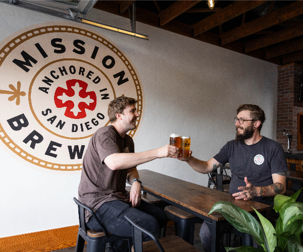 Two customers toast with glasses of beer at Mission Brewing in Kensington.