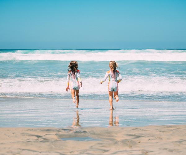 Two girls running toward the ocean in San Diego