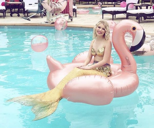 Mermaid on a pink flamingo floatie in a pool in Mission Bay San Diego