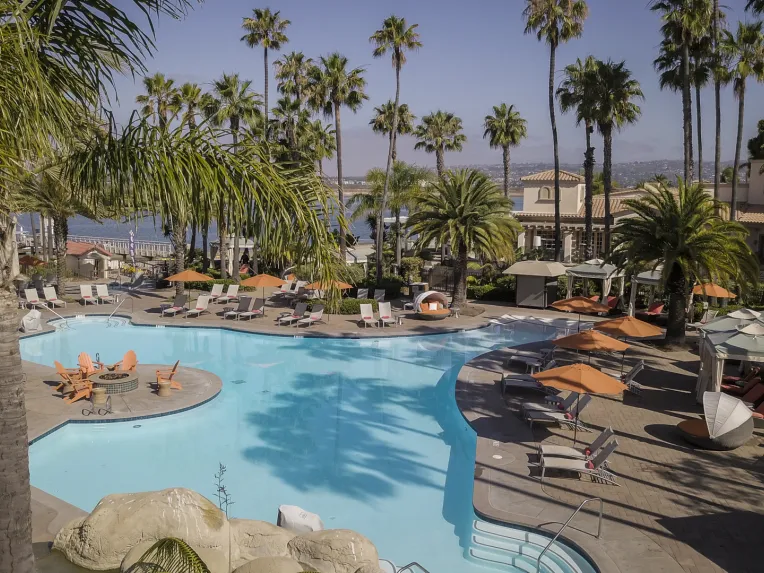 Mission Bay Resort pool surrounded by palm trees and lounge chairs under a clear blue sky located in San Diego