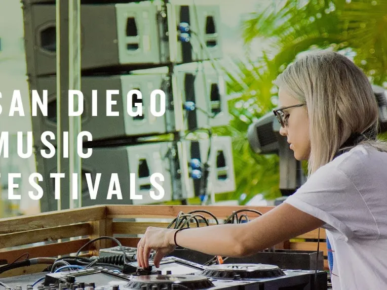 DJ wearing headphones and sunglasses performs at an outdoor event with equipment, set against a backdrop of speakers and greenery. Text reads, "San Diego Music Festivals.