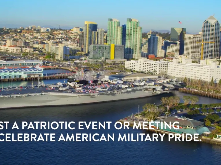 Aerial view of a large battleship docked by a waterfront city skyline, with the text: "Host a patriotic event or meeting to celebrate American military pride.