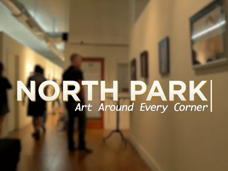 Three people view artworks displayed on the walls of a well-lit gallery. Text overlay reads: "NORTH PARK | Art Around Every Corner.