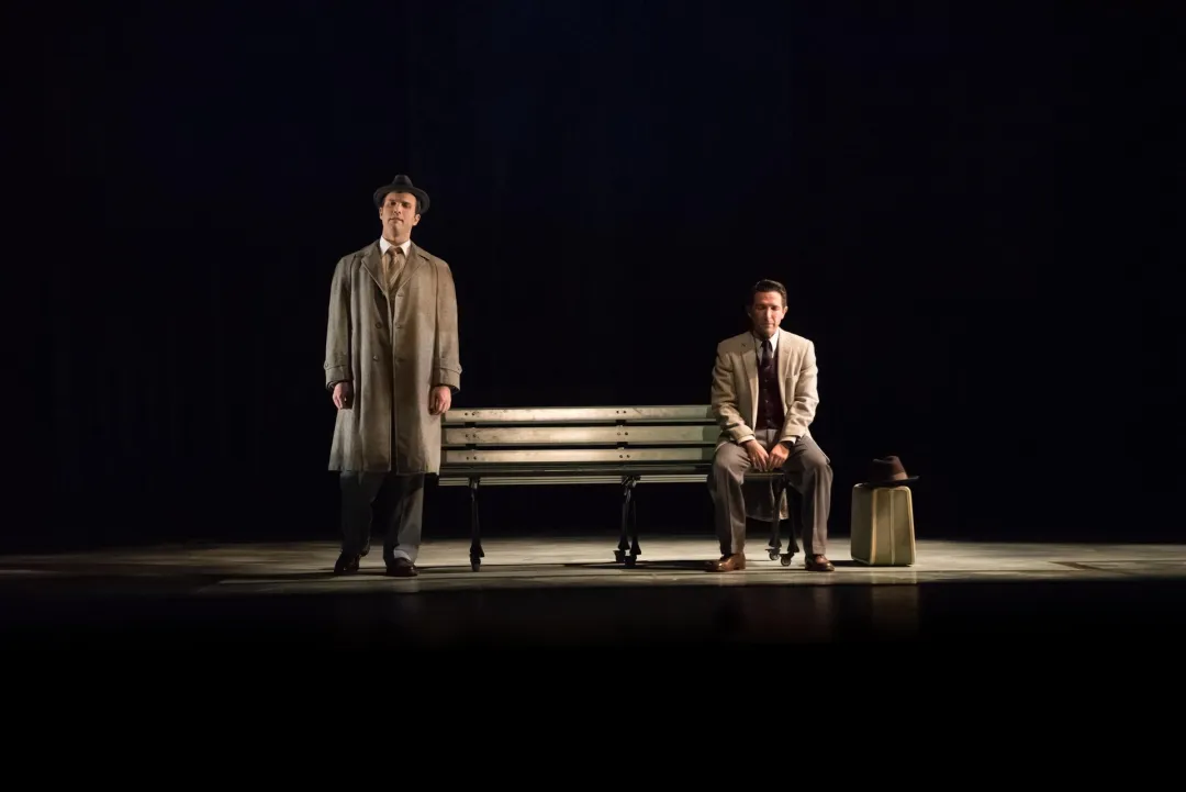 A scene of two men in a darkened stage from a San Diego Opera production.