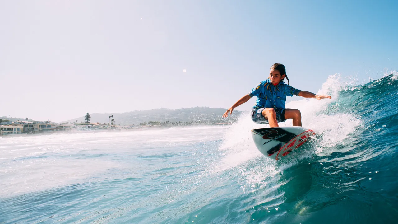 A surfer riding a wave with the coastline in the background