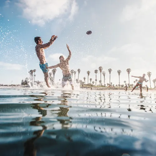 3 people playing football in the water at Mission Bay in San Diego