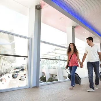 Happy couple walking across a sky bridge at the San Diego International Airport