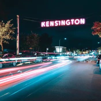 Kensington Neighborhood sign over a nighttime time-lapse of car lights streaks.