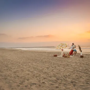 A couple dancing with each other on the beach at sunset next to a fire pit in San Diego