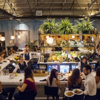 People dining at the rectangular bar of Herb & Wood in Little Italy neighborhood of San Diego, CA