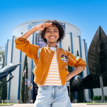 Young girl salutes outside of the San Diego Air & Space Museum in San Diego's Balboa Park