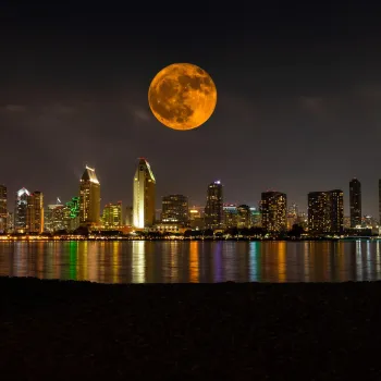 Full moon above San Diego skyline on a dark night