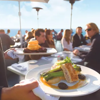 Server bring dinner plates to diners at George's at the Cove in San Diego's La Jolla