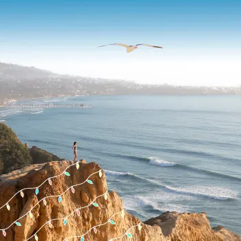 Female hiker standing atop a hill at Torrey Pines Regional State Park with some fun holiday graphics of lights superimposed
