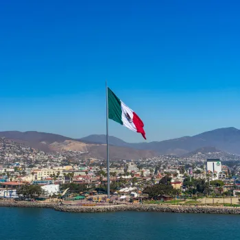 Port of Ensenada with a large flag of Mexico towing over the waterfront promenade