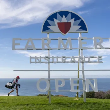 Farmers Insurance Open sign with a golfer walking behind it and the Pacific Ocean in the background