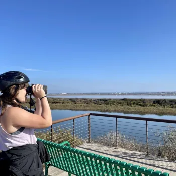 Woman with binoculars exploring a wetlands area in San Diego