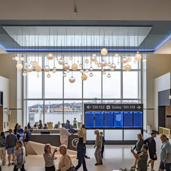 Travelers waiting at Terminal 1 San Diego Airport with art overhead