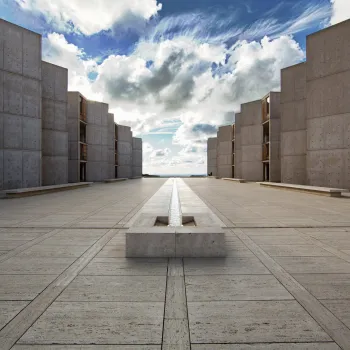 A view of the Salk Institute in the La Jolla neighborhood of San Diego, with symmetrical buildings on each side stretching to a view of the ocean on the horizon.