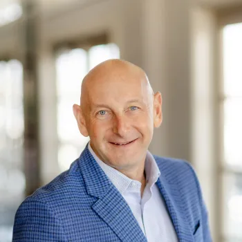Daniel Kuperschmid in a blue blazer stands in a bright indoor setting, slightly smiling.
