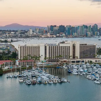 Sheraton San Diego Resort - View of a marina with yachts, a hotel, and a city skyline at sunset.