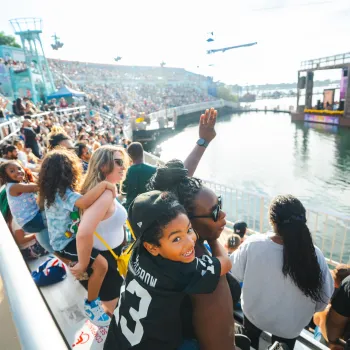 A diverse crowd watches a SeaWorld San Diego Summer Concert by the water, with excitement and smiles visible.