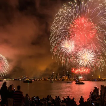 Colorful fireworks for Big Bay Boom illuminate the night sky over San Diego's waterfront for Fourth of July, with spectators watching in awe.