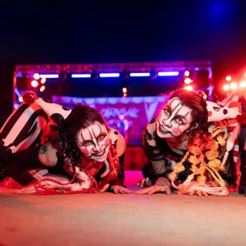 Two performers in clown-like makeup pose dramatically under colorful stage lights at SeaWorld San Diego's Howl-O-Scream halloween event.