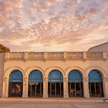 Historic Fleet Science Center with arched windows under a colorful sunset sky in Balboa Park.