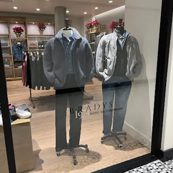 Two male mannequins dressed in casual jackets, shirts, and pants are displayed in a store window labeled "BRADY'S 1914 HOTEL DEL CORONADO.