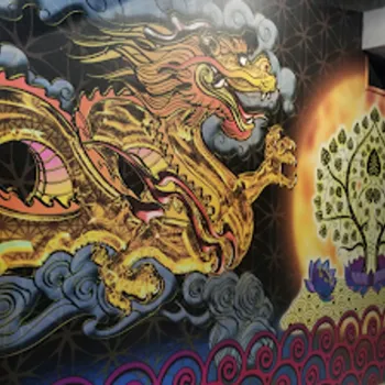A mural on a wall features a golden dragon surrounded by blue clouds and a stylized tree with a glowing yellow background.