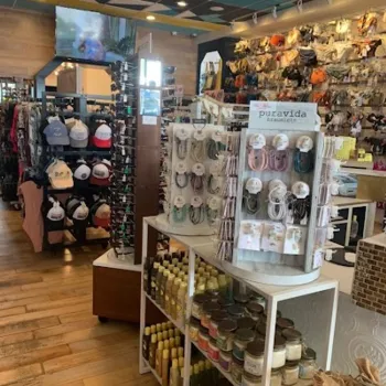 A boutique store interior displays hats, sunglasses, jewelry, candles, and hair accessories on shelves and racks, with wooden floors and a decorative ceiling.