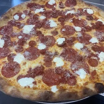 A large pepperoni pizza with melted cheese, ricotta dollops, and shredded cheese on a thin, crispy brown crust.
