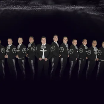A group of thirteen men in matching black mariachi suits with silver embroidery stand in a row against a dark background.