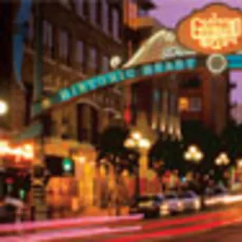 A city street scene at dusk with the illuminated Gaslamp Quarter sign arching over the road in San Diego, featuring blurred car lights and historic buildings.