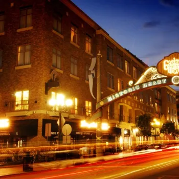 Night view of the illuminated Gaslamp Quarter Historic Heart archway sign over a street with light trails from passing cars in San Diego, California.