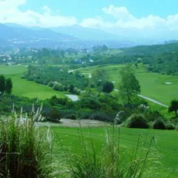 A golf course surrounded by green hills and vegetation, with distant mountains visible under a partly cloudy sky. The text "Steele Canyon" is in the top right corner.