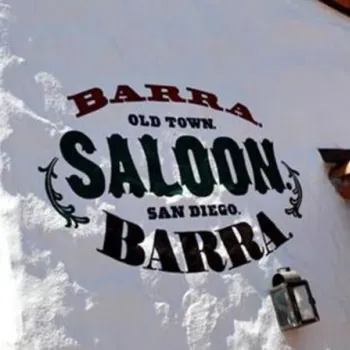 White stucco wall with painted sign reading "Barra Old Town Saloon San Diego Barra" next to a small outdoor lamp and red-tiled roof.