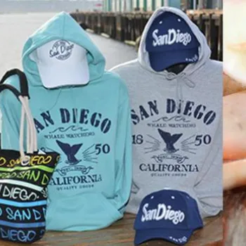 A display of San Diego souvenir shot glasses, clothing, hats, tote bags, and seashells with a "San Diego CA" sticker.