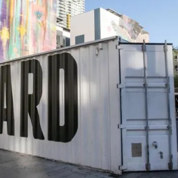 Outdoor venue with "Quartyard" painted on a large white shipping container, surrounded by urban buildings and string lights overhead.