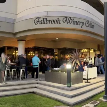 A large group of people gathered outside Fullbrook Winery Café at The Epicure and Culinary Center, with modern architecture and outdoor lighting.