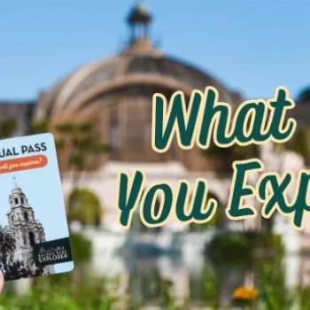 A hand holds an annual pass card in front of a domed botanical building with text that reads, "What Will You Explore?.