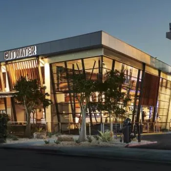 Modern industrial-style building with large windows and warm interior lighting, labeled “City Water” on the exterior, photographed at dusk.