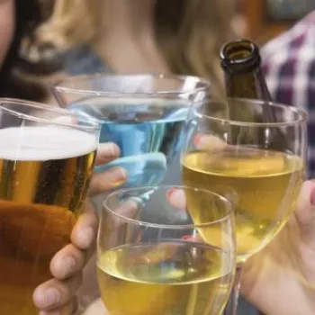 Four people clinking glasses of beer, wine, and a blue drink together in a celebratory toast.