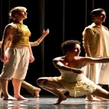 A group of dancers in light-colored costumes perform expressive movements on a dimly lit stage; text reads "A Geography of Risk & Other Dances.