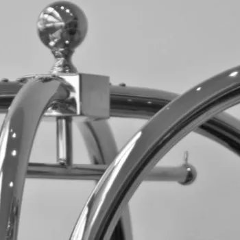 Close-up view of the top sections of several metal luggage carts, featuring curved handles and spherical knobs, against a plain light background.