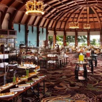 Large, elegant banquet hall with high wooden ceiling, chandeliers, and numerous tables set for a buffet-style event.