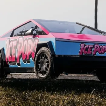 A Tesla Cybertruck with bright "Ice Pops" branding is parked outdoors on grass, featuring a blue and pink color scheme.