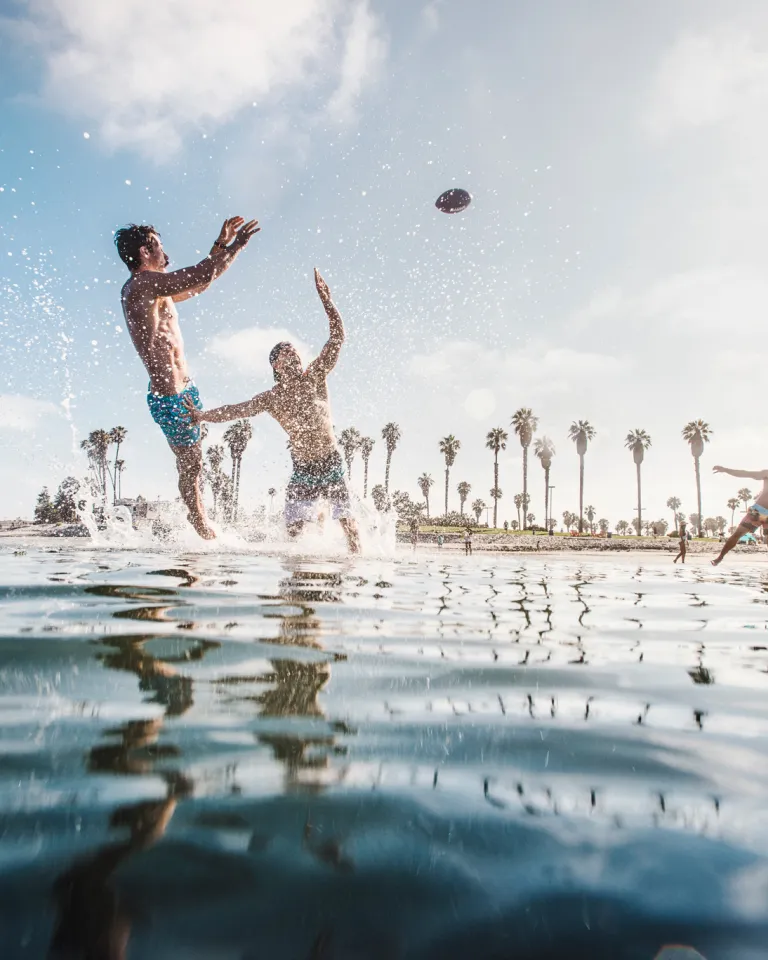 3 people playing football in the water at Mission Bay in San Diego