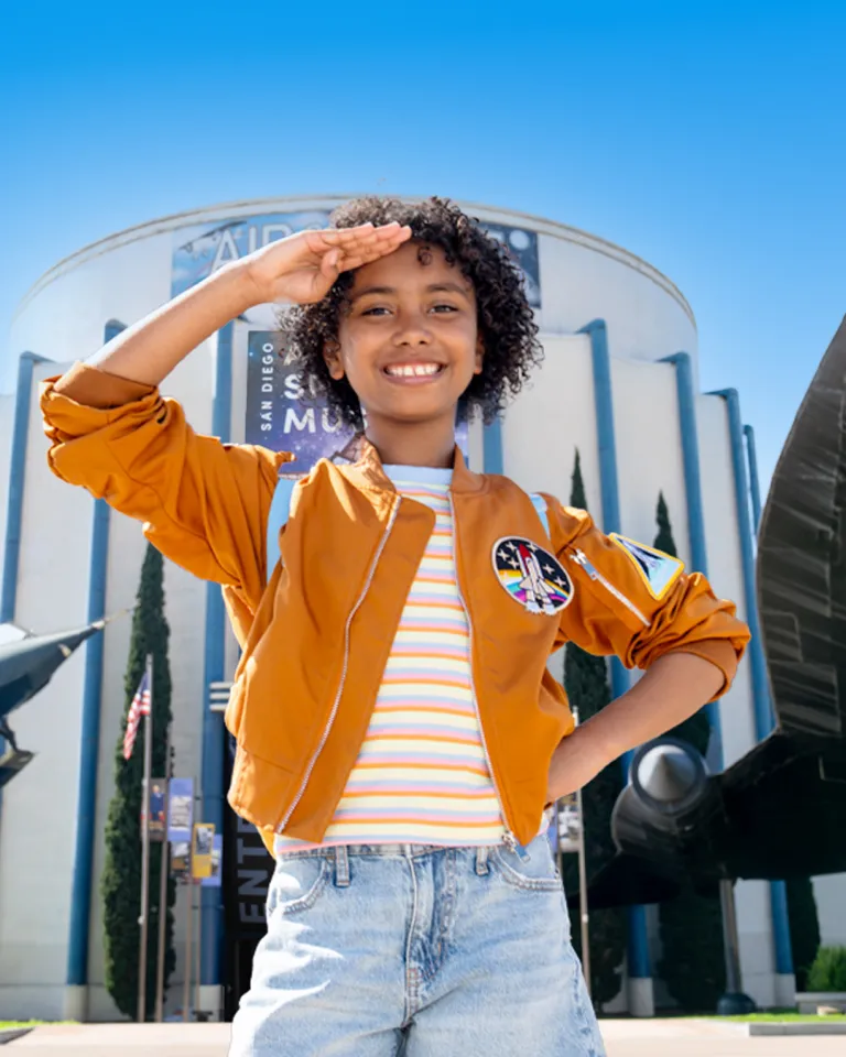 Young girl salutes outside of the San Diego Air & Space Museum in San Diego's Balboa Park